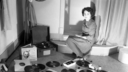 A young women posing with phonograph records and a record player.