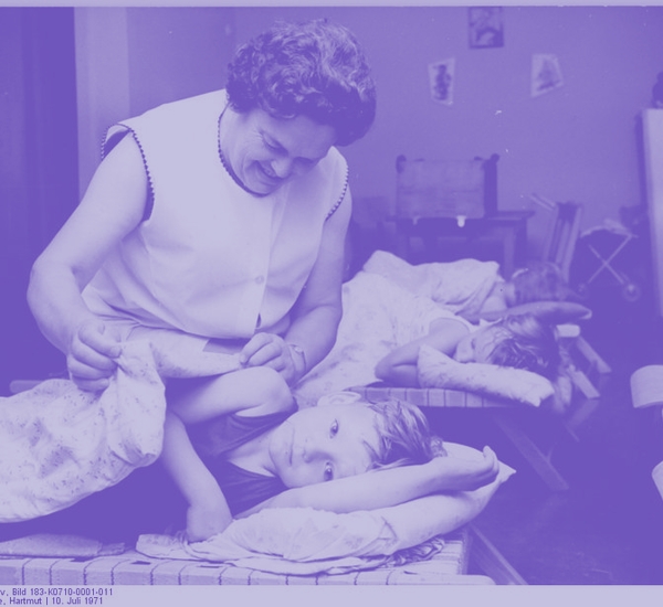 Image of a woman tucking a child into bed