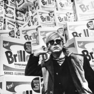 Image of Andy Warhol in front of Brillo boxes