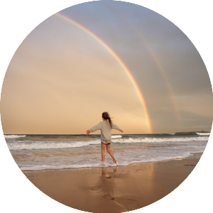Anonymous woman on beach with rainbow
