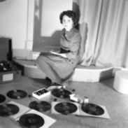 A young women posing with phonograph records and a record player.